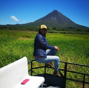 a woman sitting on the back of a truck with a mountain in the background at Casas de Campo Las Pavitas Cottages "Red Frog" in Palma