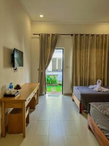 a bedroom with a bed and a desk and a window at ARECA MUINE HOMESTAY in Phan Thiet