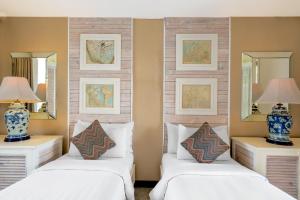 2 camas en una habitación con 2 espejos en The Kanjeng Suites Petitenget, en Seminyak