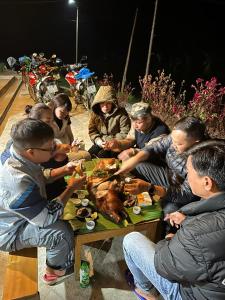 a group of people sitting around a table with a turkey at Hoàng nam Homestay in Quang Ba