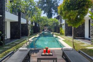 a swimming pool in the middle of a yard with benches at The Kanjeng Suites & Villas Sanur in Sanur