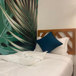 a white bed with a blue pillow and a plant at Bahandi Hotel in General Luna