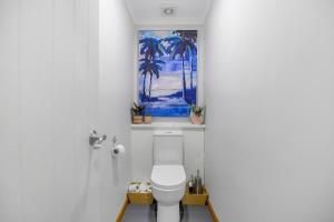 a bathroom with a toilet with a painting on the wall at Zodiac Bay Lake Retreat in Rotorua +36 photos