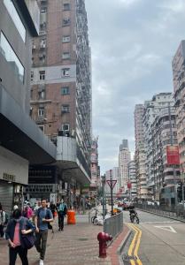 persone che camminano in una strada di città con edifici alti di Johnson Hostel a Hong Kong