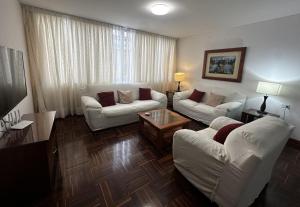 una sala de estar con 2 sofás blancos y una mesa. en San Isidro Olivar 2 bedroom Apartment, en Lima