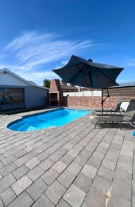 un patio con sombrilla y piscina en Family Holiday Home Rental in Port Elizabeth en Lorraine
