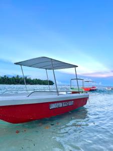 Ein rotes Boot sitzt im Wasser in der Unterkunft Langoyon Beach Resort 