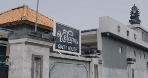 a guest house sign on the side of a building at Kelana Guest House in Lovina