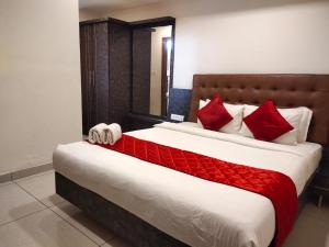 a bedroom with a large bed with red pillows at GOLDEN AMULYA REST WINGS in Yelahanka