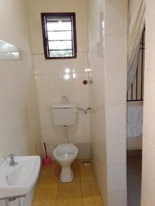 a bathroom with a toilet and a sink and a window at Cingaki Hotel in Mombasa