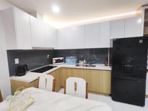een keuken met witte kasten en een zwarte koelkast bij Chung cư cao cấp Asiana Capella quận 6 in Ho Chi Minh-stad