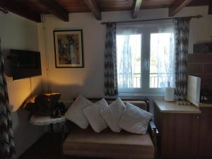 un soggiorno con divano, cuscini e finestra di VILLA DOROTHY STUDIO a Delfi
