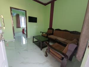 uma sala de estar com um sofá e uma televisão em Sili Homestay em Madikeri