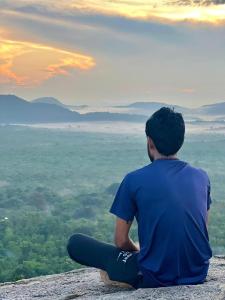 a man sitting on top of a mountain looking at the sunset at Grand freedom in Sigiriya