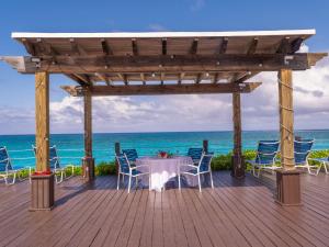 a table and chairs on a wooden deck with the ocean at Deluxe Sea View Villas at Paradise Island Beach Club Resort in Creek Village