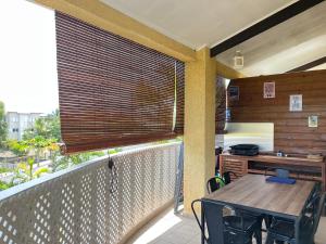 un balcón con una mesa de madera y una persiana de madera en una terraza en Bel appart Étang salé La réunion en Étang-Salé les Bains