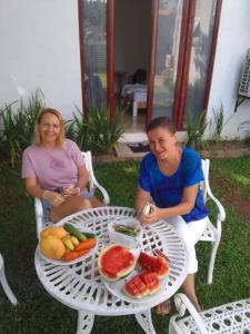 zwei Frauen sitzen an einem Tisch mit einem Obstteller in der Unterkunft Grand Avalon 