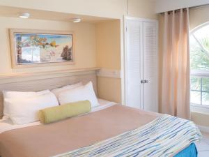 a bedroom with a bed with white pillows and a window at Garden View Villas at Paradise Island Beach Club in Creek Village