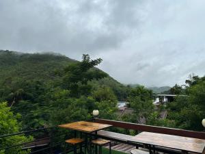 einen Balkon mit einem Tisch und Bergblick in der Unterkunft ชอว์ งาทอง รีสอร์ต Chor Ngar Thong Erawan in Kanchanaburi