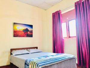 Schlafzimmer mit einem Bett und einem Fenster mit lila Vorhängen in der Unterkunft Villa 163 in Negombo