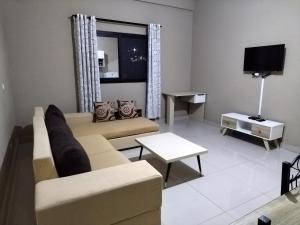salon z kanapą i telewizorem w obiekcie Milestone City - Appartements à louer w Antananarywie