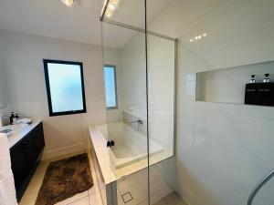 La salle de bains est pourvue d'une douche, d'une baignoire et d'un lavabo. dans l'établissement Entire house, 5br luxury hideaway, à Narellan