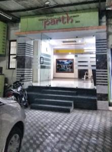Hotel Parth Inn, WARDHA في Wardha: واجهة متجر مع سلالم في موقف للسيارات