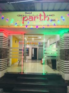 Hotel Parth Inn, WARDHA في Wardha: مدخل الفندق مع وجود لافته للحفلات والاضائه