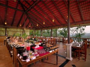 un ristorante con tavoli e sedie con cibo sopra di Tapovana The Fern Heritage Resort, Sakleshpur a Sakleshpur
