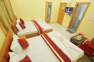 a hotel room with three beds and a television at LOTUS HOTEL AND BANQUET in Kolkata