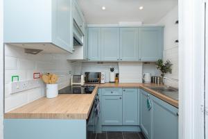 a kitchen with blue cabinets and wooden counter tops at Stunning 1BR Flat, 3 min to Elephant & Castle Tube in London