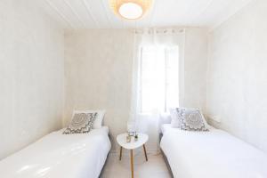 a white room with two beds and a table at Theros Cottage Nafplio in Nafplio