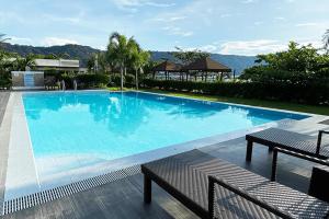 une grande piscine bleue avec deux bancs à côté dans l'établissement RSAM Beach Resort by Cocotel, à Nasugbu