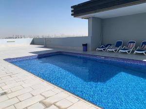 a swimming pool with chairs sitting next to a building at 2BR W Pool-20 min to DXB APT & Dubai Mall in Dubai