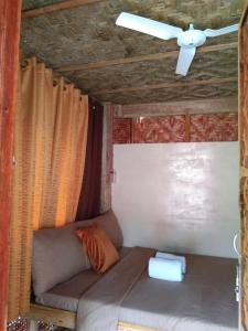 Sofá en habitación con ventilador de techo en Chloe’s Paradise Hostel, en Batuan