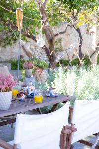 a wooden table with two white chairs and orange juice at Theros Cottage Nafplio in Nafplio