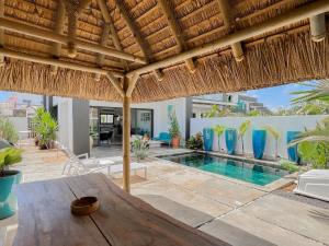 a villa with a swimming pool and a straw roof at Résidence Celestial - Premium 3 bedrooms Villa with volcanic stone Pool in Grand Baie