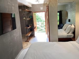a bedroom with a bed and a living room with a door at Ikopa Hôtel Madagascar in Antananarivo