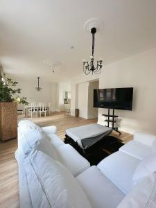 sala de estar con sofá blanco y TV de pantalla plana en Zentralmoers 140m2 Hbf Nah, en Moers
