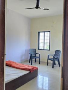 een slaapkamer met 2 stoelen en een bed en een plafond bij Two Brother's Hotel lodging And Restaurant WARDHA in Wardha