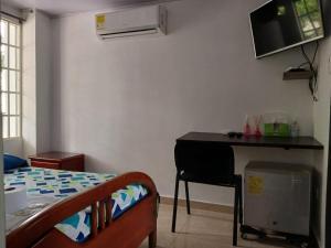 1 dormitorio con 1 cama y escritorio con TV en la pared en HABITACIÓN INDEPENDIENTE y APARTAESTUDIO MONOAMBIENTE, en Barranquilla
