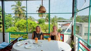 deux femmes assises à une table sur un balcon dans l'établissement Nest, à Cochin