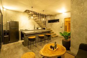 eine Küche mit einer Theke, einem Tisch und einem Kühlschrank in der Unterkunft Casaluna 1, Canggu industrial townhouse with private pool in Dalung