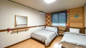 a bedroom with two beds and a mirror on the wall at Smile Resort in Sokcho