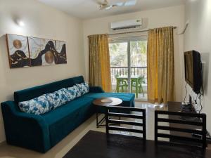 a living room with a blue couch and a table at Golden Bird Heritage in Arpora