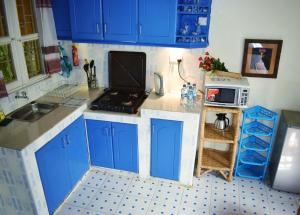 a small kitchen with blue cabinets and a microwave at Ose Cottages in Kisumu