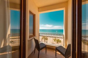 a balcony with chairs and a view of the ocean at Hotel Riva Del Sole in Cefalù