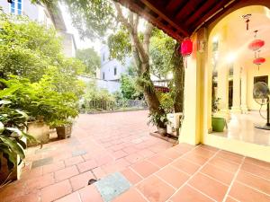 a porch with a brick walkway with a tree at Lee Homestay in Hanoi