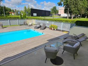 a swimming pool with chairs and a table on a wooden deck at "Indian Summer" Apartment in Viljandi