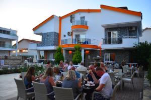 a group of people sitting at a restaurant in front of a building at Rose Garden Boutique Hotel in Akbük